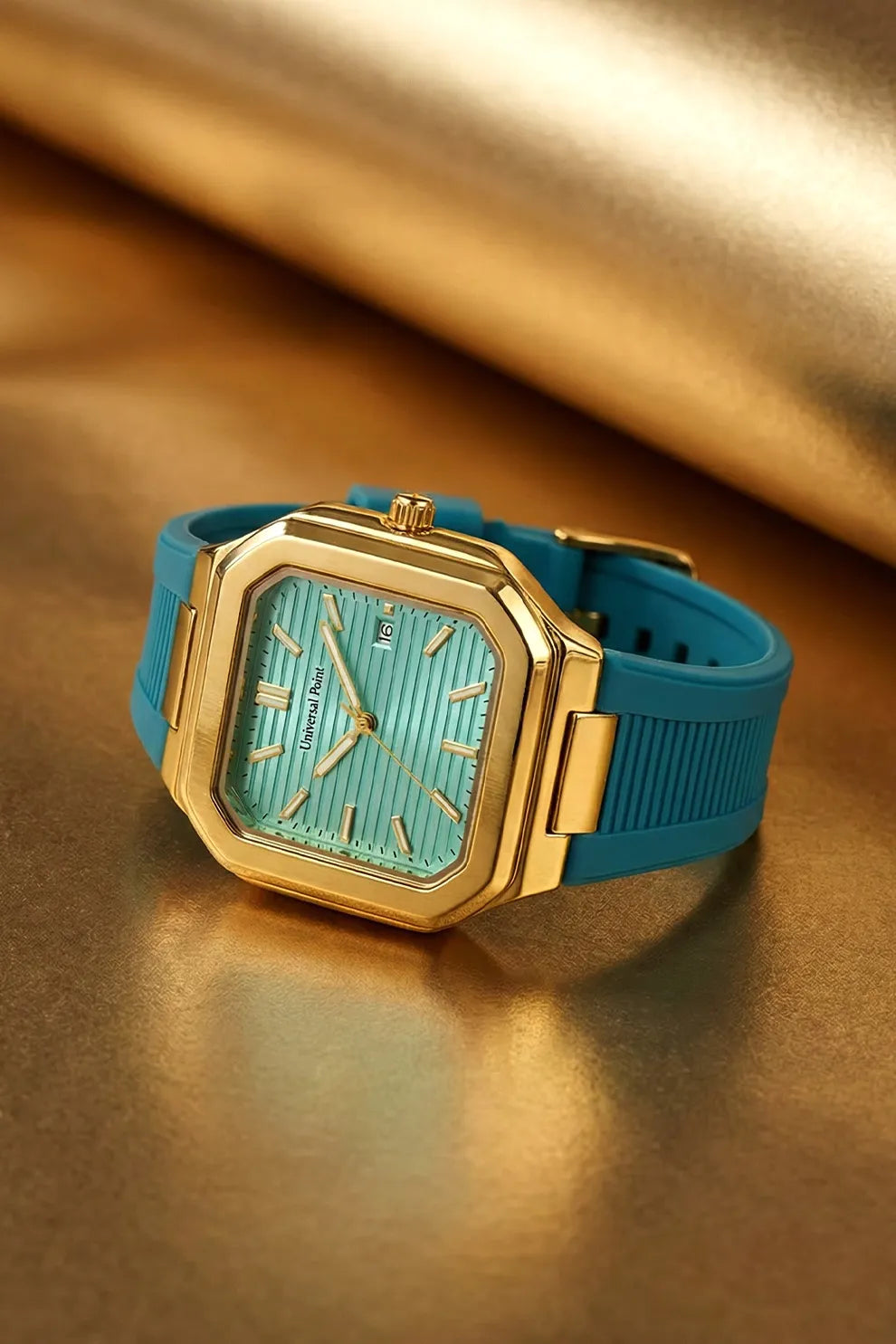 Gold watch with a turquoise strap on a reflective gold surface